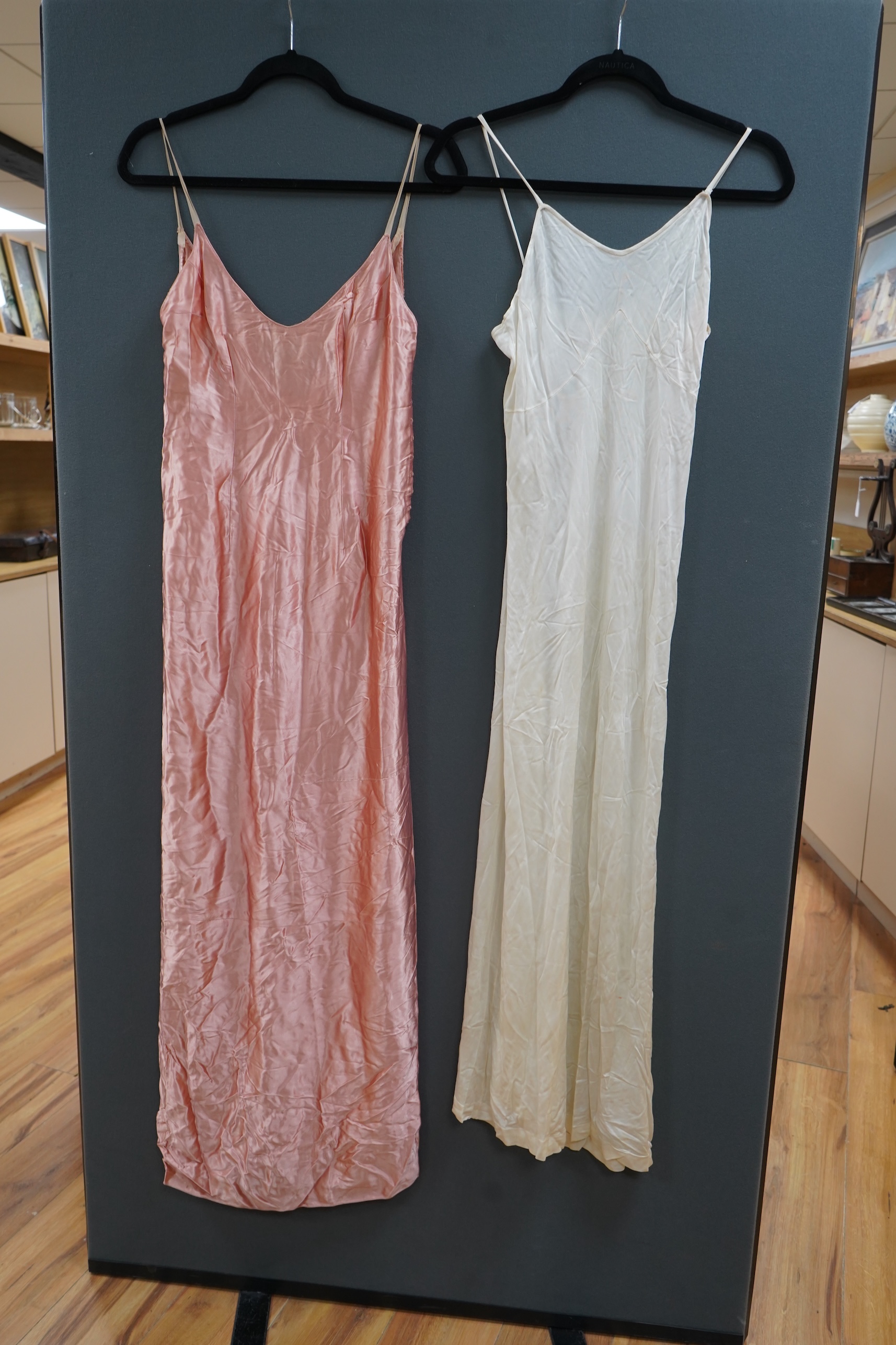 Two late 19th early 20th century long baby night gowns and two shorter baby gowns, together with a pink satin ladies full length slip and a similar cream silk stockinette slip, the bodices worked on baby dresses are embr